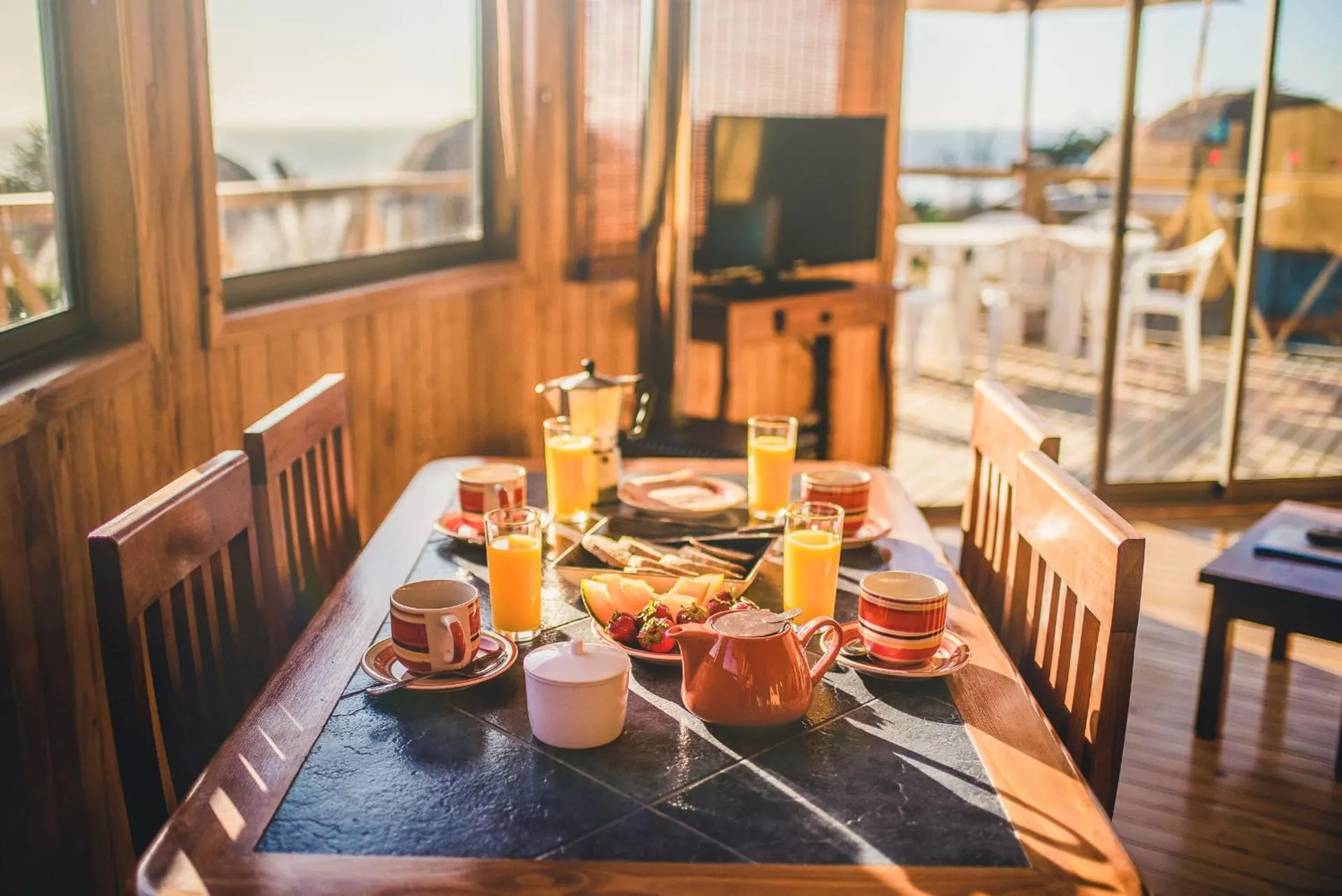 Dining table with a breakfast served, next to a large window with a view of the terrace.