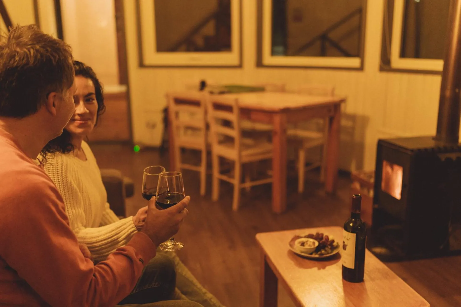 Dining area of a dome with a couple at the table, wine glasses and windows in the background.