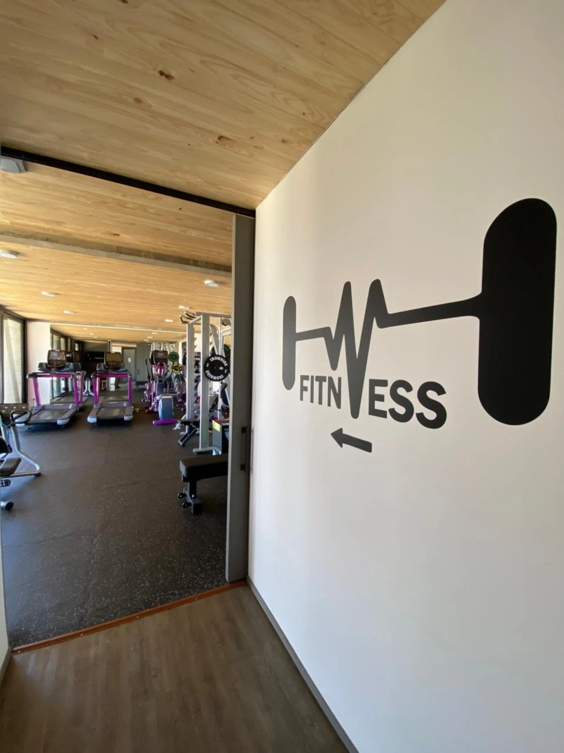 Gym entrance, with the Fitness sign on the wall and the machines in the back.