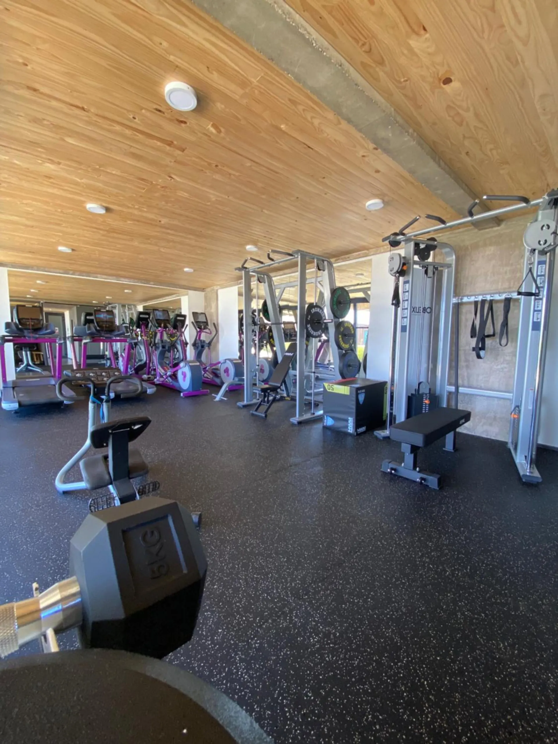 Strength machines and free weights on a black rubber floor.