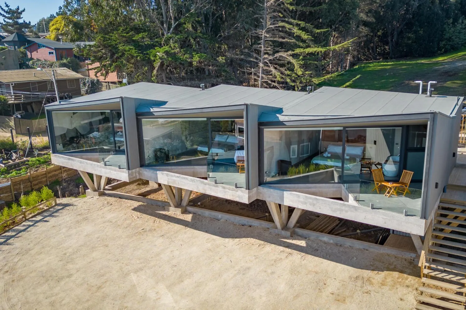 The suites seen from above: gray volumes with large windows, over a stone terrace.