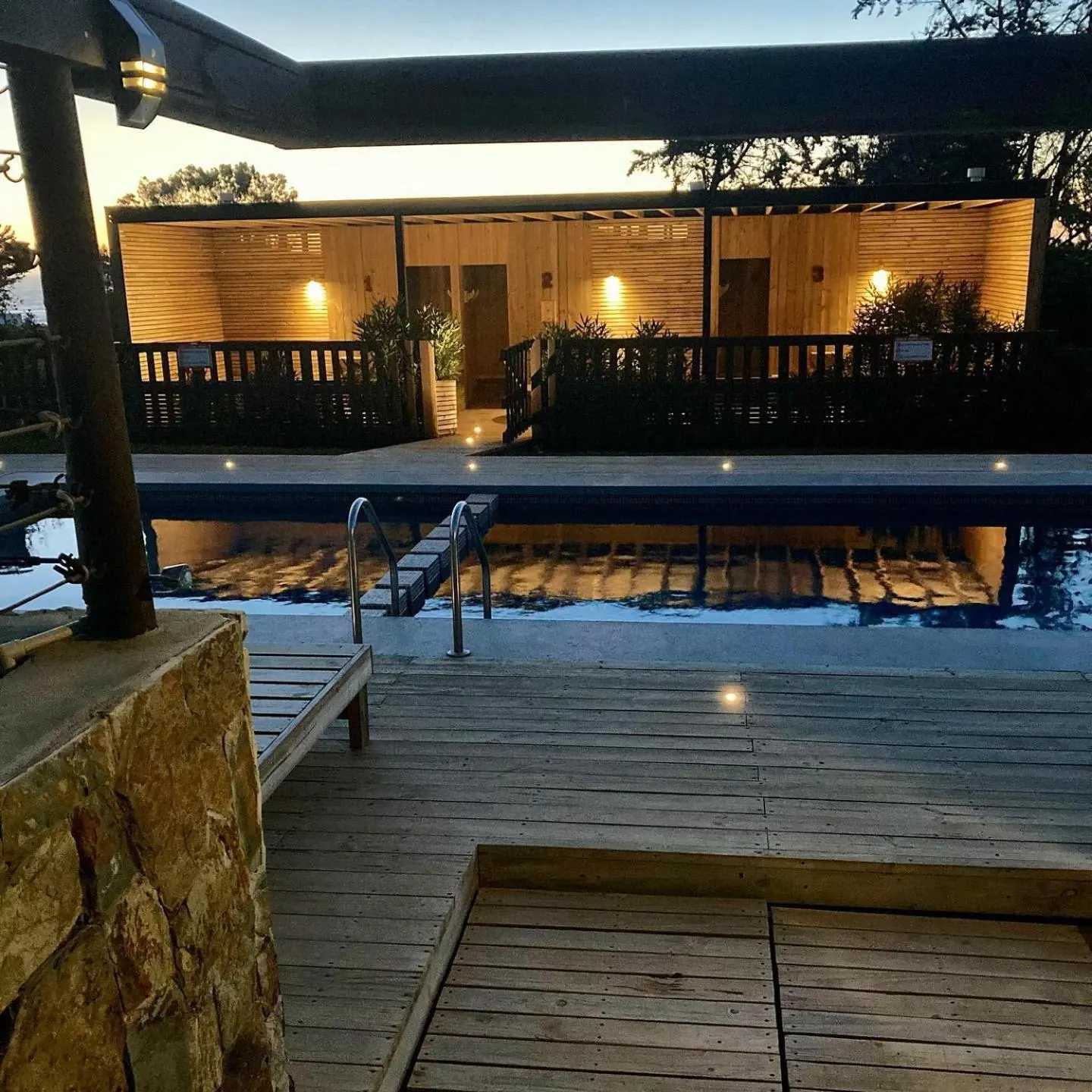 Wooden terrace with the warm lights of the accommodation lit at dusk.